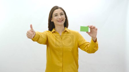 Foto de Mujer joven aislada sobre fondo blanco sosteniendo algo verde, mostrando un producto, sonriente y alegre. Las personas creativas pueden reemplazar la caja verde con cualquier producto que quieran.. - Imagen libre de derechos
