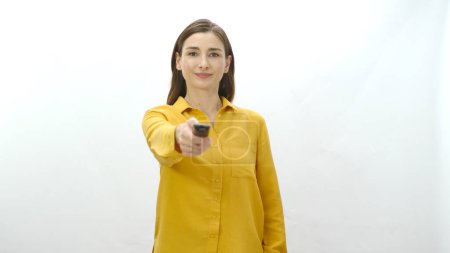 Photo for Woman holding tv remote control in hand isolated on white background. The woman searches for the program she wants to watch on television channels. Undecided woman portrait. - Royalty Free Image