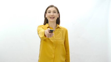 Photo for Woman holding tv remote control in hand isolated on white background. The woman searches for the program she wants to watch on television channels. Undecided woman portrait. - Royalty Free Image