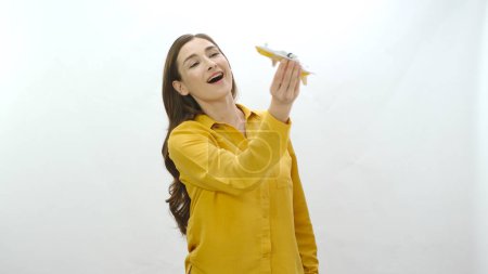 Photo for Young woman playing with a small toy model passenger plane isolated on white background. Not being able to live your childhood. Cute woman are playing with a toy airplane. - Royalty Free Image