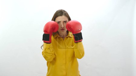 Photo for Coping with difficulties in business life. Young woman with boxing gloves isolated on white background. Young woman exercising with boxing gloves, nervously punching camera. Strong woman portrait. - Royalty Free Image