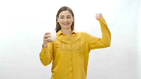 Foto de Retrato de carácter de una joven mostrando sus bíceps fuertes mientras bebe leche. Una mujer que dice que es fuerte bebiendo leche. Aislado sobre fondo blanco. - Imagen libre de derechos
