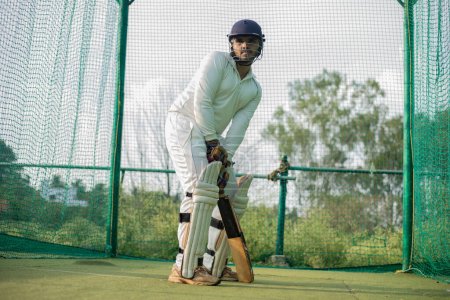 Téléchargez les photos : Batteur de cricket en attente pour bowler au bol. Le joueur est prêt à faire plus de pratique dans les filets. Joueur concentré prêt à jouer, photo de haute qualité - en image libre de droit