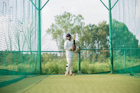 Cricket Batsman waiting for bowler to bowl. The player is ready to do more practice in the nets. Focused player ready to play, High quality photo. 