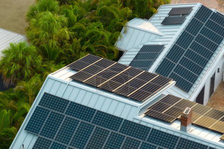 Luftaufnahme eines neuen amerikanischen Hausdachs mit blauen Photovoltaik-Sonnenkollektoren zur Erzeugung sauberer ökologischer elektrischer Energie. Erneuerbarer Strom mit Null-Emissions-Konzept.