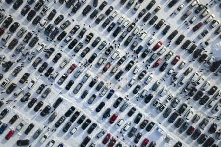 Vista aérea del lote de mercado abierto de vehículos con muchos coches en venta estacionados y clientes de personas caminando en invierno.