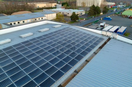 Vue aérienne de panneaux solaires photovoltaïques bleus montés sur le toit d'un bâtiment industriel pour produire de l'électricité écologique verte. Production de concept d'énergie durable.