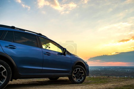 Foto de Landscape with blue off road car at sunset, Traveling by auto, adventure in wildlife, expedition or extreme travel on a SUV automobile. - Imagen libre de derechos