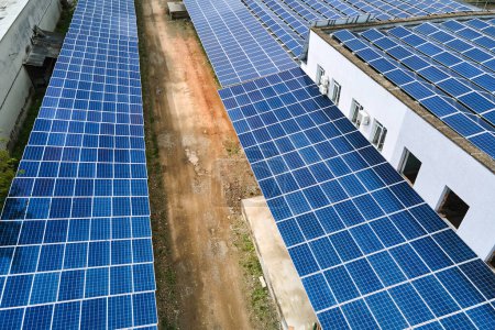 Vista aérea de paneles solares fotovoltaicos azules montados en el techo de un edificio industrial para producir electricidad ecológica verde. Producción del concepto de energía sostenible.