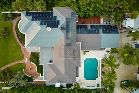 Luftaufnahme eines teuren amerikanischen Hausdachs mit blauen Photovoltaik-Sonnenkollektoren zur Produktion sauberer ökologischer elektrischer Energie. Investitionen in erneuerbaren Strom zur Altersvorsorge.