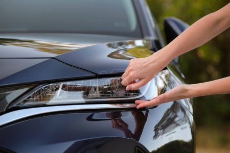 Female driver hands checking headlight of her new car. Purchase of vehicle concept.