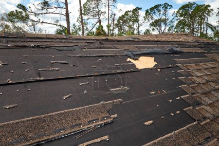 Photo for Wind damaged house roof with missing asphalt shingles after hurricane Ian in Florida. Repair of home rooftop concept. - Royalty Free Image