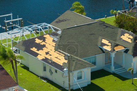 Damaged house roof with missing shingles after hurricane Ian in Florida. Consequences of natural disaster.