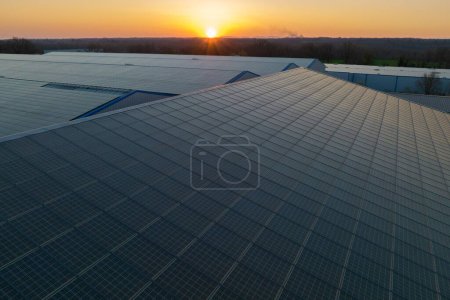Blaue Photovoltaik-Sonnenkollektoren auf dem Hausdach zur Erzeugung sauberen ökologischen Stroms bei Sonnenuntergang. Erstellung eines Konzepts für erneuerbare Energien.