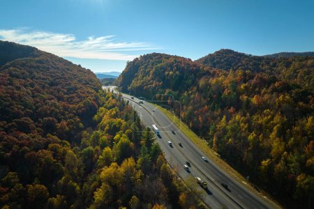 Blick von oben auf den I-40 Freeway in North Carolina Richtung Asheville durch die Appalachen im goldenen Herbst mit schnell fahrenden Lastwagen und Autos. Bundesweites Verkehrskonzept.