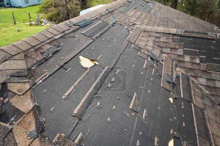 Toit de la maison endommagé par le vent avec des bardeaux d'asphalte manquants après l'ouragan Ian en Floride. Réparation du concept de toit de la maison.