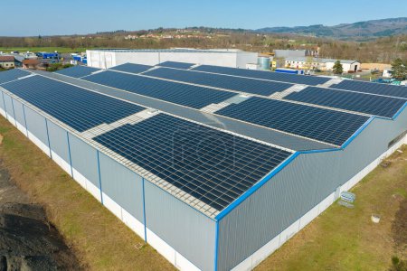 Vue aérienne de panneaux solaires photovoltaïques bleus montés sur le toit d'un bâtiment industriel pour produire de l'électricité écologique verte. Production de concept d'énergie durable.