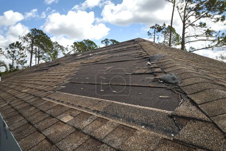Toit de la maison endommagé par le vent avec des bardeaux d'asphalte manquants après l'ouragan Ian en Floride. Réparation du concept de toit de la maison.