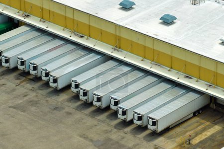 Foto de Vista aérea de un gran centro de distribución comercial con muchos camiones descargando y cargando productos minoristas para su posterior envío. Concepto de economía global. - Imagen libre de derechos