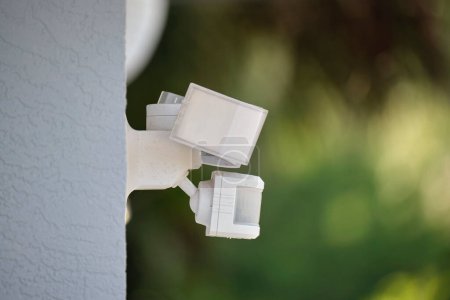 Sensor de movimiento con detector de luz montado en la pared exterior de la casa privada como parte del sistema de seguridad.