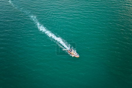 Téléchargez les photos : Vue aérienne du yacht blanc nageant sur les vagues de mer avec surface ondulée. Bateau à moteur en mouvement sur l'océan. - en image libre de droit