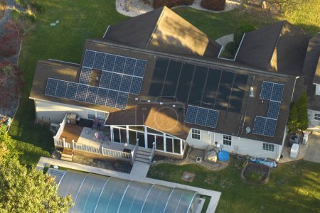 Téléchargez les photos : Grande maison neuve aux Etats-Unis avec toit recouvert de panneaux solaires photovoltaïques pour la production d'énergie électrique écologique propre dans les zones rurales de banlieue. Concept de maison autonome. - en image libre de droit