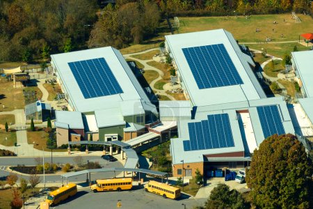 Téléchargez les photos : Roof of american school building covered with photovoltaic solar panels for production of electric energy. Renewable energy concept. - en image libre de droit