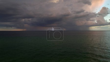 Téléchargez les photos : Nuages orageux foncés se formant sur un ciel sombre pendant la saison des pluies abondantes sur la surface de la mer en soirée. - en image libre de droit
