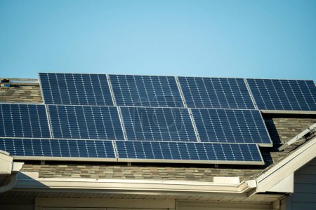 Luftaufnahme eines normalen amerikanischen Hausdaches mit blauen Photovoltaik-Sonnenkollektoren zur Produktion sauberer ökologischer elektrischer Energie. Erneuerbarer Strom mit Null-Emissions-Konzept.