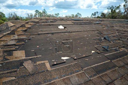 Photo for Wind damaged house roof with missing asphalt shingles after hurricane Ian in Florida. Repair of home rooftop concept. - Royalty Free Image