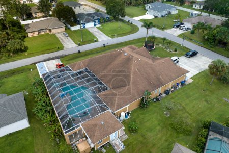 Téléchargez les photos : Vue aérienne d'une maison privée américaine contemporaine typique avec une enceinte extérieure en lanai couvrant une grande piscine. Concept de vie en plein air et de s'amuser dans l'eau de la piscine sur le soleil d'été Floride. - en image libre de droit