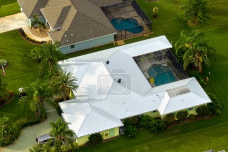 Vista aérea de la típica casa privada americana contemporánea con techo cubierto con tejas de asfalto y césped verde en el patio.