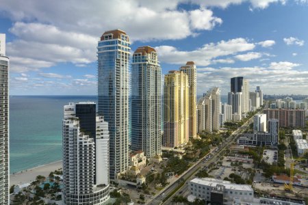 View from above of luxurious highrise hotels and condos on Atlantic ocean shore in Sunny Isles Beach city. Urban street with busy traffic. American tourism infrastructure in southern Florida.
