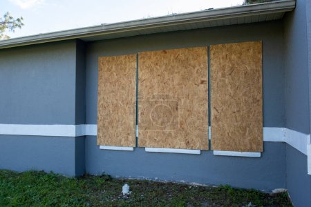 Plywood storm shutters for hurricane protection of house windows. Protective measures before natural disaster in Florida.