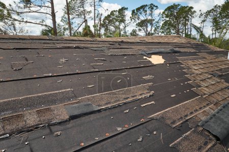 Foto de El viento dañó el techo de la casa con la falta de tejas de asfalto después del huracán Ian en Florida. Reparación del concepto de la azotea. - Imagen libre de derechos