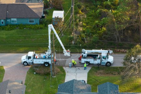 Electrical service company restoring power repairing damaged power lines after hurricane Ian in Florida suburban area.