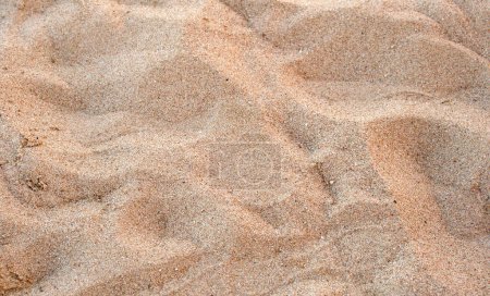 Vista plana de la superficie limpia de arena amarilla que cubre la playa costera. Textura arena.