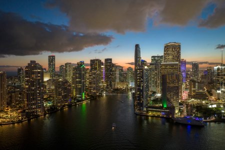 View from above of brightly illuminated high skyscraper buildings in downtown district of Miami Brickell in Florida, USA. American megapolis with business financial district at night.