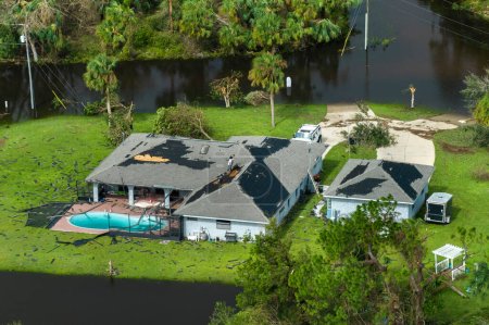 Destroyed by hurricane strong wind private house with damaged rooftop and swimming pool lanai enclosure in Florida residential area. Natural disaster and its consequences.