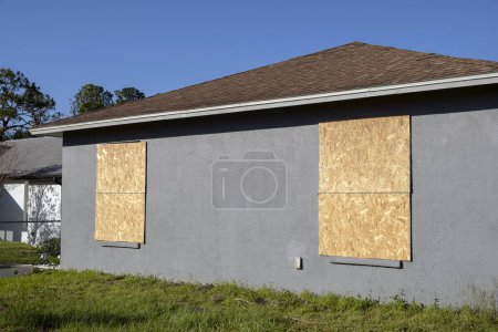 Photo for Boarded up windows with plywood storm shutters for hurricane protection of residential house. Protective measures before natural disaster in Florida. - Royalty Free Image