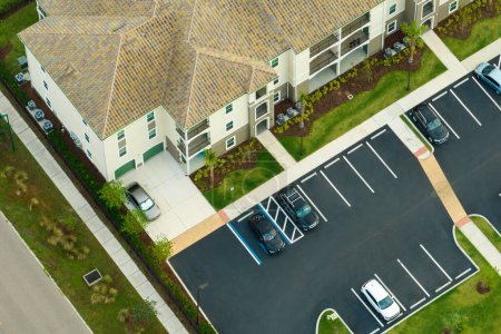 Foto de Vista aérea de los coches estacionados en lugares de estacionamiento en el edificio de apartamentos americanos en la zona residencial de Florida. Nuevos condominios familiares como ejemplo de desarrollo de viviendas en suburbios de EE.UU.. - Imagen libre de derechos