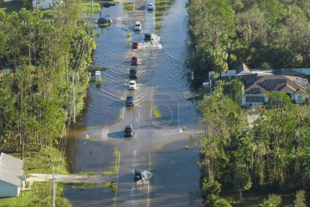 Flooded road in Florida after heavy hurricane rainfall. Aerial view of evacuating cars and surrounded with water houses in suburban residential area.