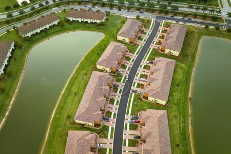 Foto de Vista aérea de las casas muy llenas en la Florida cerrado clubes de vida con agua del lago en el medio. Viviendas familiares como ejemplo de desarrollo inmobiliario en suburbios americanos. - Imagen libre de derechos