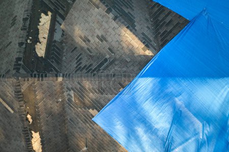 Téléchargez les photos : Vue aérienne du toit endommagé de la maison de l'ouragan Ian recouvert d'une bâche de protection bleue contre les fuites d'eau de pluie jusqu'au remplacement des bardeaux d'asphalte. - en image libre de droit