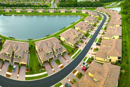 Téléchargez les photos : Vue aérienne de maisons familiales étroitement situées avec des étangs de rétention pour éviter les inondations en Floride zone de banlieue fermée. Développement immobilier en banlieue américaine. - en image libre de droit