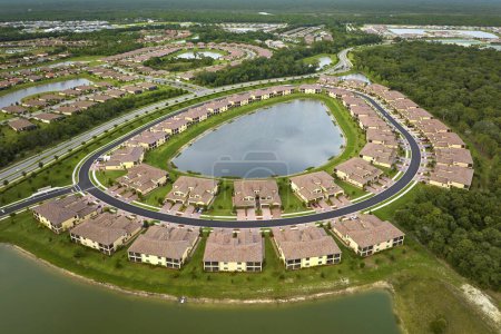 Téléchargez les photos : Vue aérienne de maisons familiales étroitement situées avec des étangs de rétention pour éviter les inondations en Floride zone de banlieue fermée. Développement immobilier en banlieue américaine. - en image libre de droit