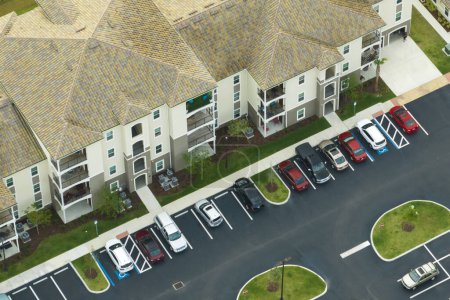 Foto de Coches aparcados en la plaza de aparcamiento de apartamentos nuevos en la zona suburbana de Florida. Vivienda familiar en barrio tranquilo. Desarrollo inmobiliario en suburbios americanos. - Imagen libre de derechos