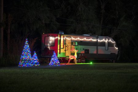 Téléchargez les photos : Camionnette de camping-car sur la cour avant avec des décorations de Noël brillamment éclairées. Décor extérieur de la maison caravane pour les vacances d'hiver. - en image libre de droit