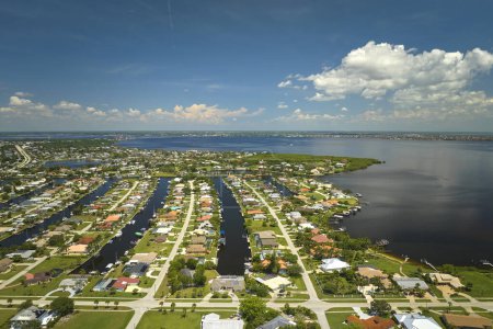 Aerial view of residential suburbs with private homes located on gulf coast near wildlife wetlands with green vegetation on sea shore. Living close to nature concept.