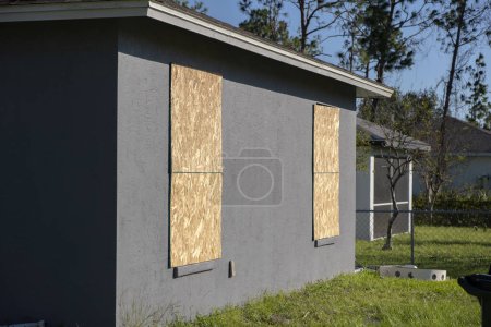 Photo for Plywood mounted as storm shutters for hurricane protection of house windows. Protective measures before natural disaster in Florida. - Royalty Free Image